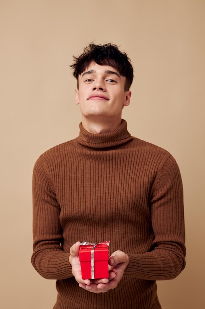 Portrait of a young man stylish hairstyle brown turtleneck gift box isolated background unaltered