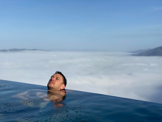 Foto ritratto di un giovane che nuota in una piscina contro il cielo