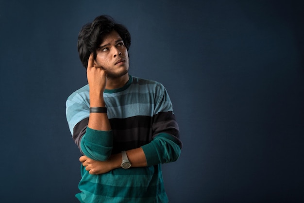 Portrait of a young man thinking on a dark background