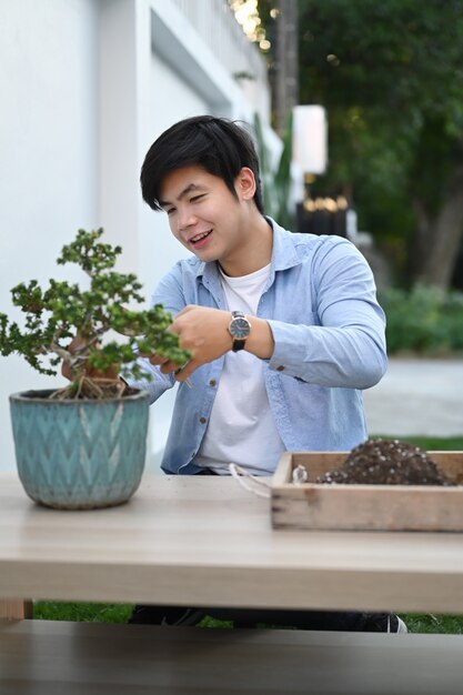 Portrait of a young man trimming bonsai tree at home