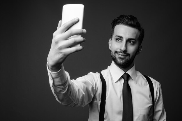 Foto ritratto di un giovane che usa un telefono cellulare su uno sfondo nero
