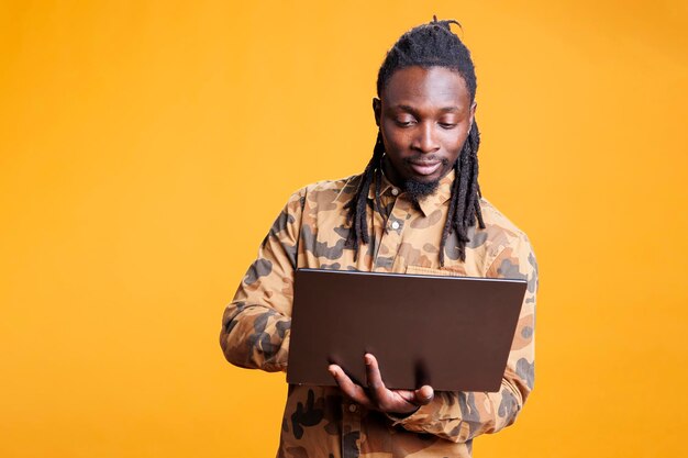 Portrait of young man using mobile phone against yellow background