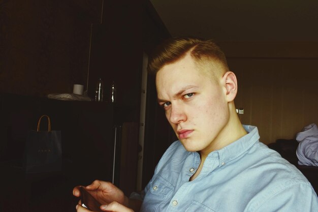 Photo portrait of young man using mobile phone at home