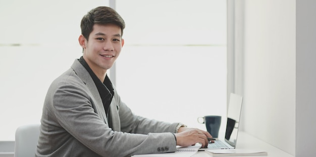 Portrait of young man using phone while sitting on table