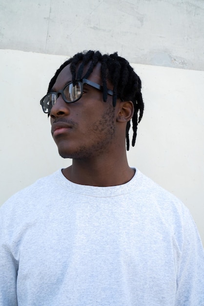 Portrait of young man wearing eyeglasses standing against wall