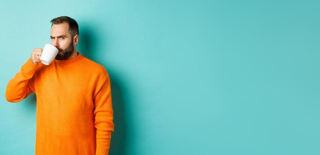 Portrait of young man wearing hat standing against blue background