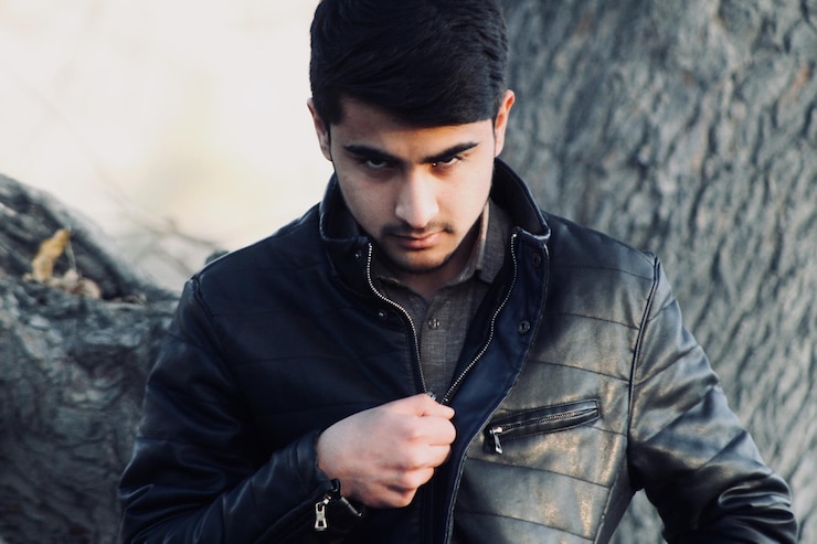 Photo portrait of young man wearing leather jacket while standing against tree