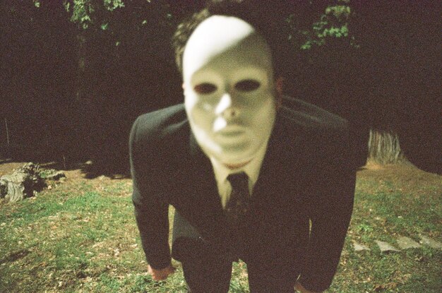 Photo portrait of young man wearing mask while standing on grassy field