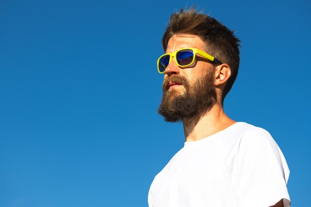 Portrait of young man wearing sunglasses against clear blue sky