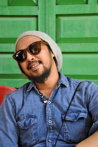 Photo portrait of young man wearing sunglasses against door