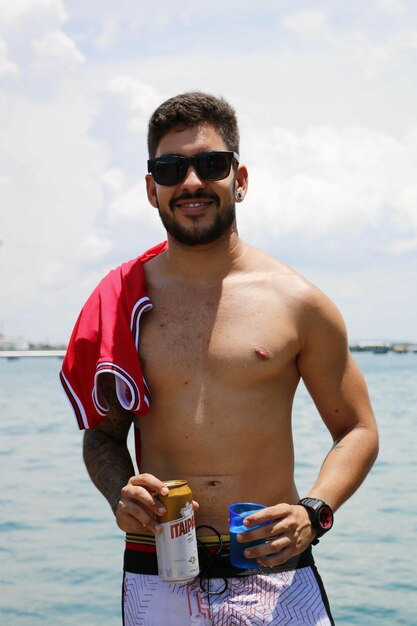 Photo portrait of young man wearing sunglasses standing against sea