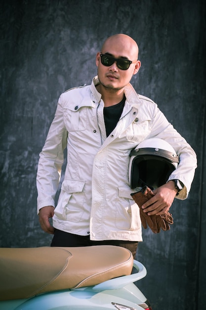 Photo portrait of young man wearing sunglasses standing against wall