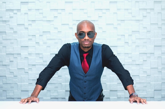 Photo portrait of young man wearing sunglasses while standing against wall