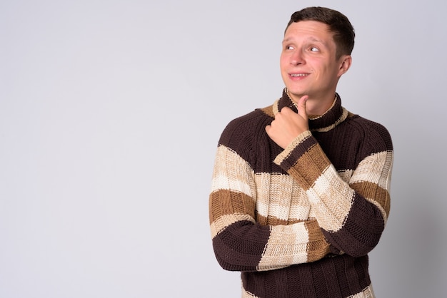 Portrait of young man wearing turtleneck sweater ready for winter against white wall