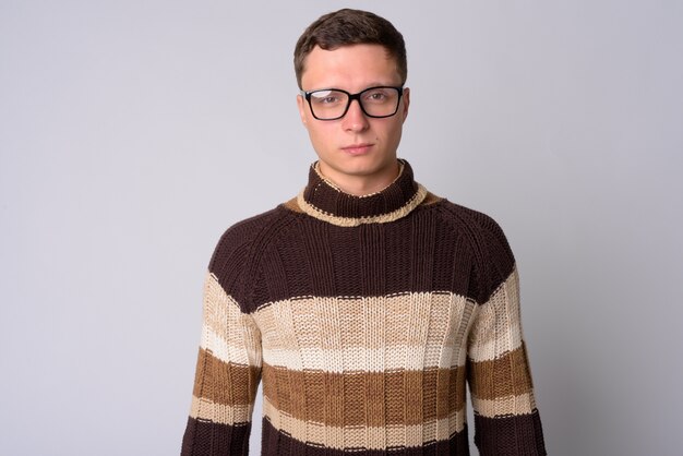 Portrait of young man wearing turtleneck sweater ready for winter against white wall