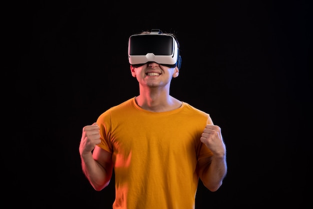 Portrait of young man wearing vr headset on dark wall