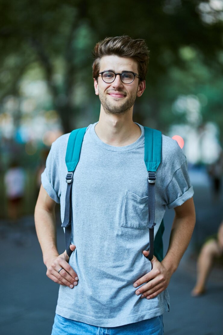 Photo portrait of young man with backpack standing at park