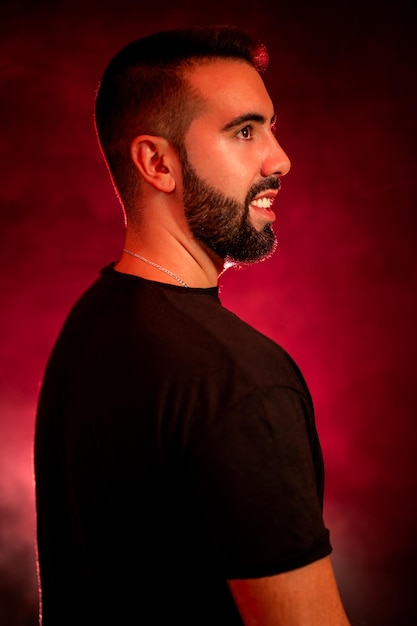 Portrait of a young man with beard on a red and black background with smoke