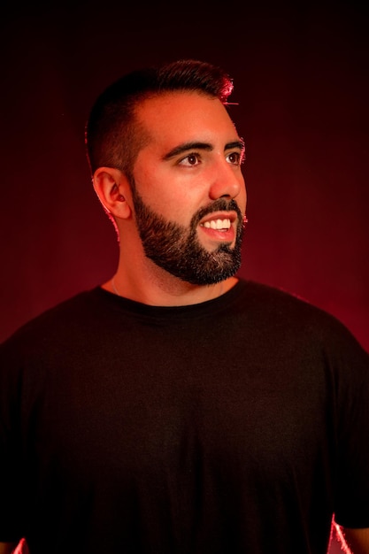 Portrait of a young man with beard on a red and black background with smoke