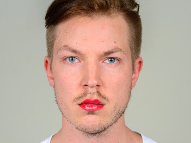 Portrait of young man with beard stubble wearing makeup