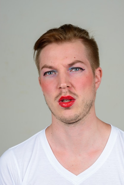 Portrait of young man with beard stubble wearing makeup