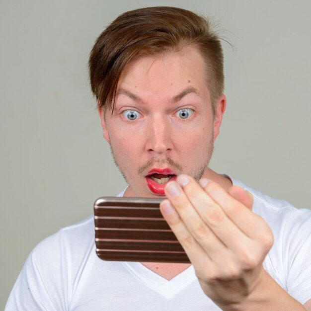 Portrait of young man with beard stubble wearing makeup