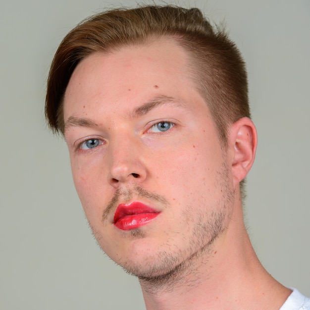 Portrait of young man with beard stubble wearing makeup