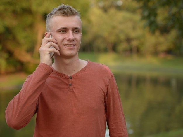 Portrait of young man with blond hair at the park outdoors