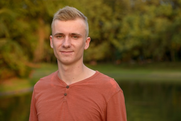 Portrait of young man with blond hair at the park outdoors