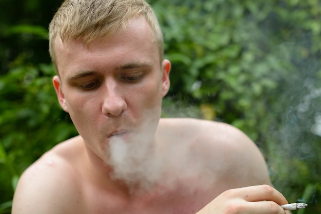 Portrait of young man with blond hair shirtless in the streets outdoors