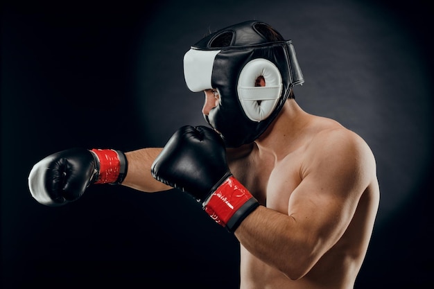 Portrait of a young man with a Boxing helmet and gloves on a dark background