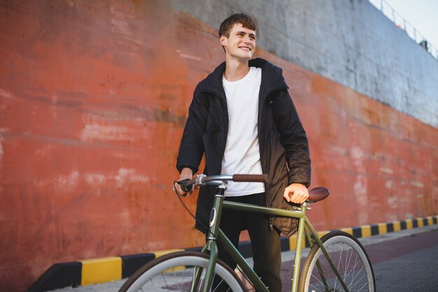 Portrait of young man with brown hair standing with bicycle