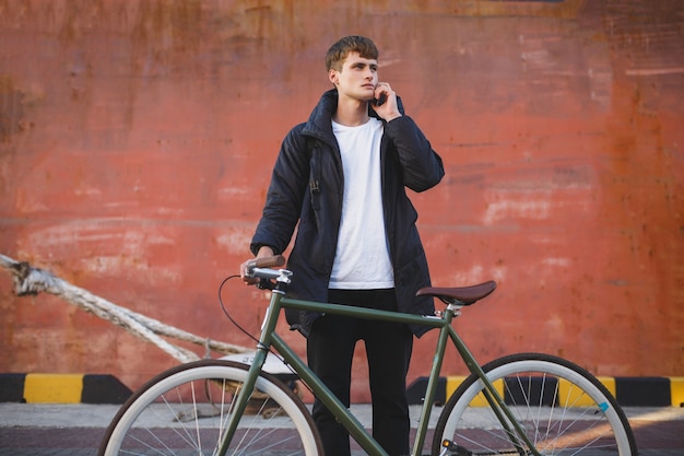 Portrait of young man with brown hair standing with bicycle