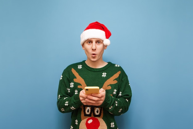 portrait young man with Christmas hat holding phone