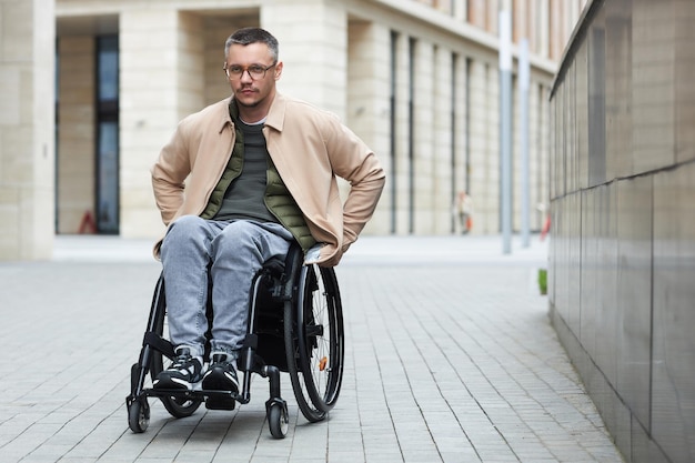 Portrait of young man with disability riding along the streets in wheelchair