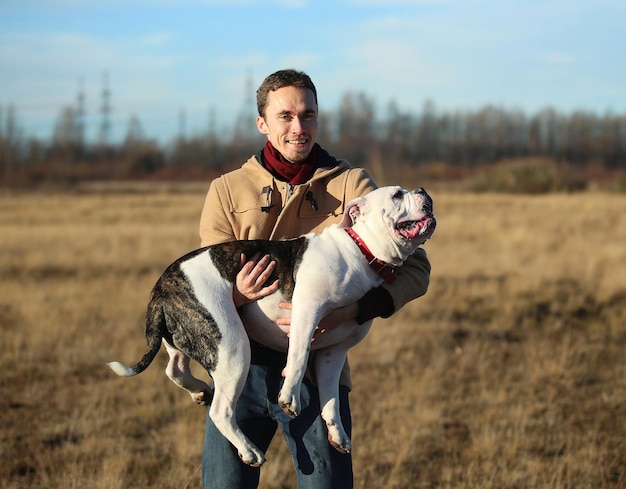 portrait of young man with dog standing on field