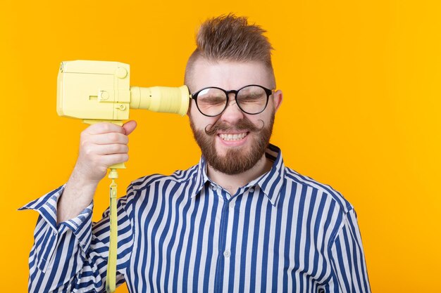 Portrait of young man with eyeglasses against yellow background