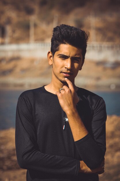 Photo portrait of young man with hand on chin standing outdoors