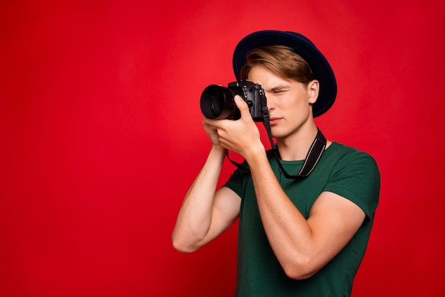 portrait young man with hat holding camera