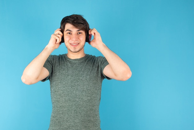 Portrait of young man with headphones on head against blue .