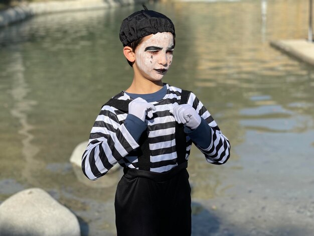 Foto ritratto di un giovane con un abito di pantomima in piedi contro il lago