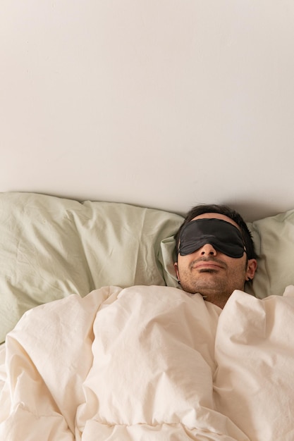 Photo portrait of young man with sleep mask in bed