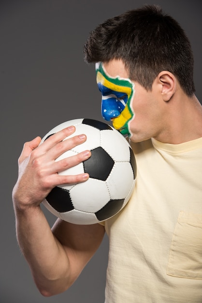 Portrait of young man with soccer ball and brazilian flag.