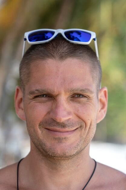 Portrait of a young man with sunglasses resting on the tropical beach, close up