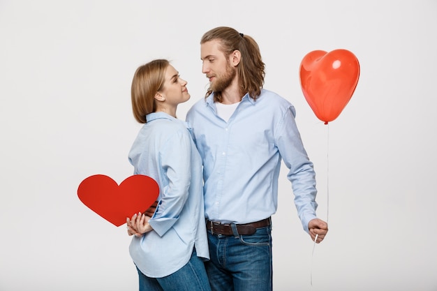 Portrait of young man and woman holding a heart- shaped balloon and paper