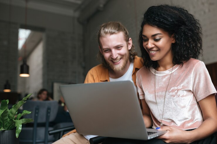 Portrait of young man and woman sitting in restaurant and working on laptop