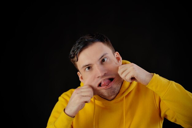 Портрет молодого человека в желтой толстовке с гримасничающим лицом