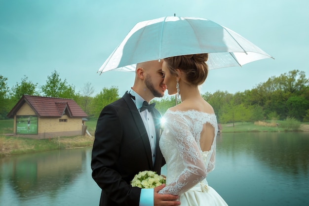 Portrait of young married couple kisses under an umbrella