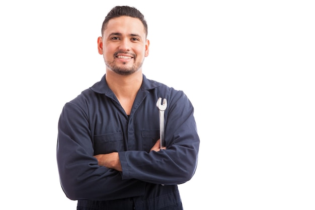 Portrait of a young mechanic holding a wrench and smiling, ready to fix cars