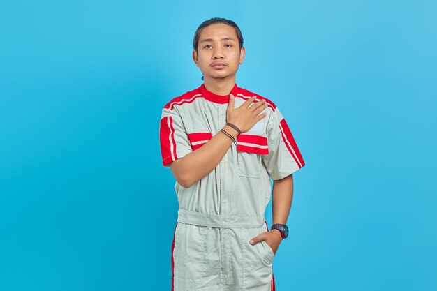 Portrait of young mechanic man greeting with big smile on his face isolated on blue background